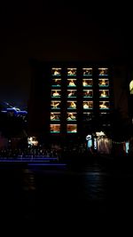 Illuminated building in city against sky at night