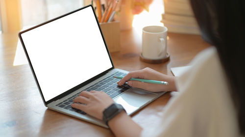 Midsection of woman using mobile phone on table