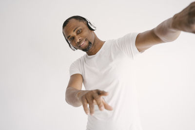 Portrait of man wearing headphones gesturing against white background