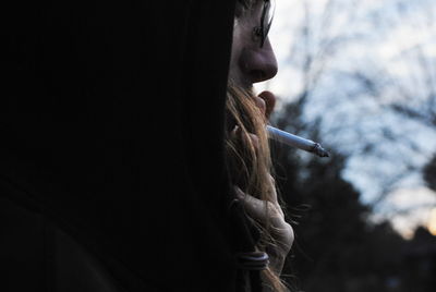 Close-up of man smoking cigarette against sky