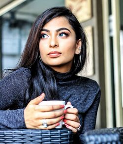 Thoughtful young woman holding coffee cup in cafe