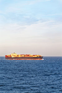 Scenic view of cargo ship in open sea on sunny day