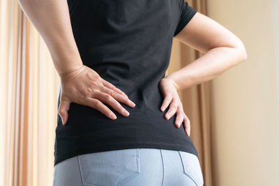 Midsection of woman touching wall at home