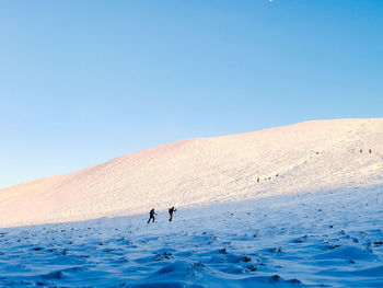 People on land against clear blue sky