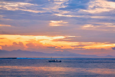 Scenic view of sea against cloudy sky at sunset