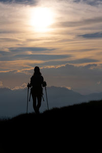 Silhouette man photographing on field against sky during sunset