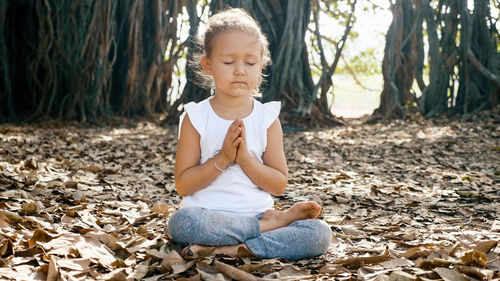 Full length of cute girl sitting on land