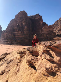 Full length of child on rock against sky