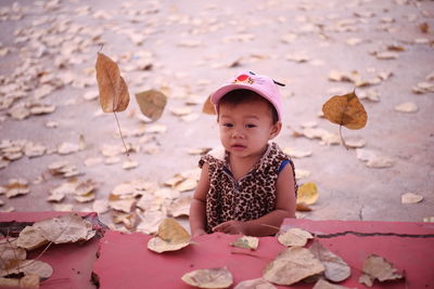 Cute girl standing amidst autumn leaves on road