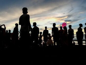 Silhouette people on beach against sky during sunset