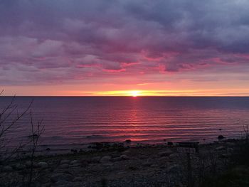 Scenic view of sea against cloudy sky during sunset