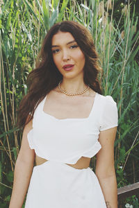 Portrait of young woman standing against plants