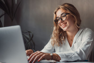 Portrait of young woman using laptop at office