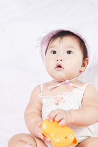 Cute baby girl sitting on bed at home