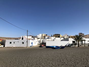 Houses on beach against clear blue sky