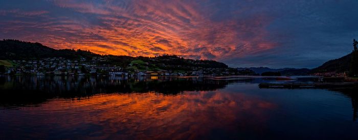 Scenic view of lake against dramatic sky during sunset