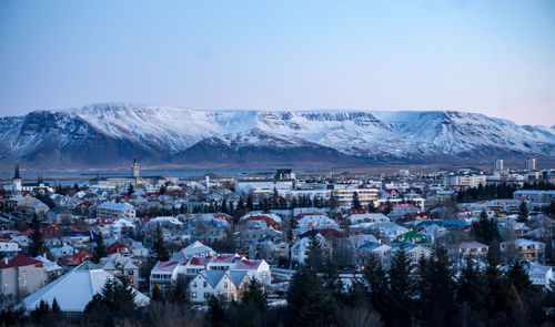 Aerial view of townscape and snowcapped mountains against sky