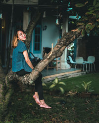 Portrait of woman sitting on tree trunk