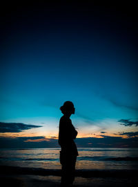 Silhouette man standing on beach against sky during sunset