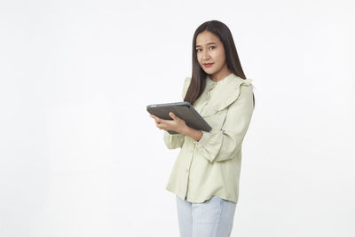 Portrait of a smiling young woman standing against white background