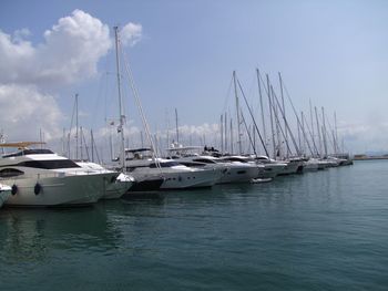 Sailboats moored on harbor against sky