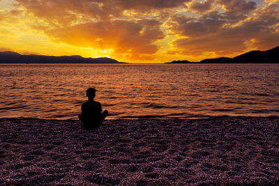 Silhouette man looking at sea against sky during sunset