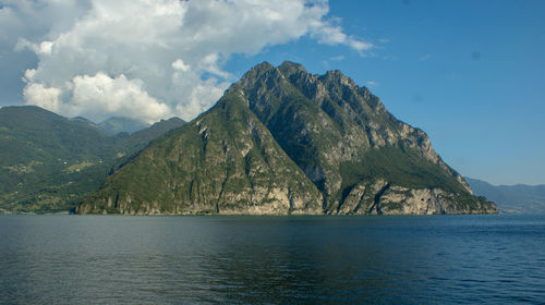 Scenic view of sea by mountains against sky