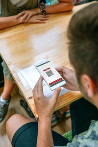 High angle view of man using smart phone sitting at cafe