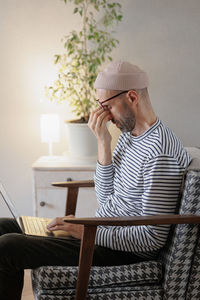 Side view of frustrated man sitting on chair