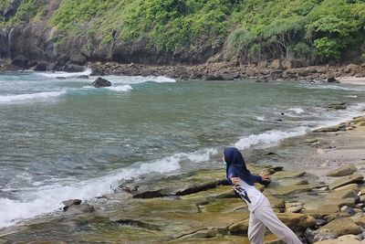 Man surfing on rock at sea shore