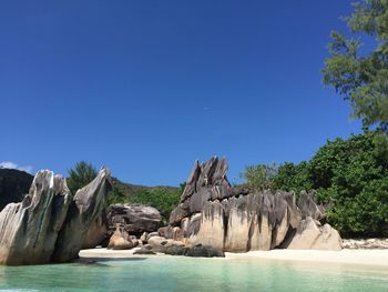 Rocks at beach against clear blue sky