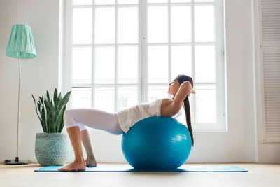 Young woman exercising with fitness ball at home