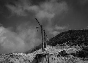 Low angle view of cross on land against sky