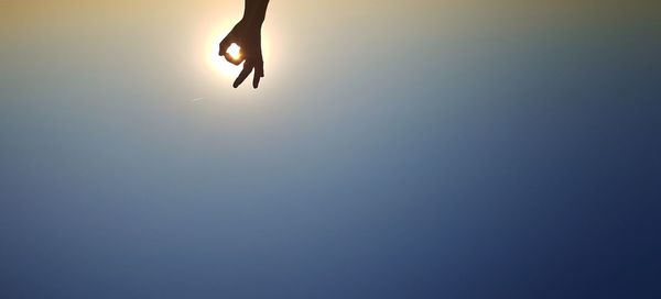 Low section of silhouette woman jumping against sky during sunset