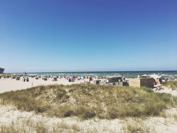 People on beach against clear blue sky