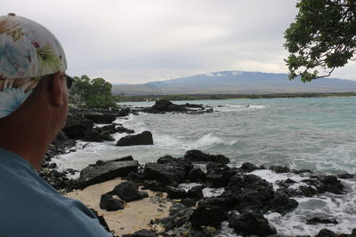 Rear view of mature man standing at beach against sky