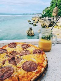 Close-up of drink on table at beach against sky