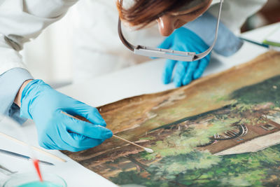 Oil painting cleaning, female conservator removing dirt from an old oil painting