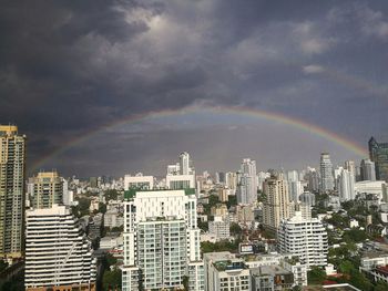 Rainbow over cityscape against sky