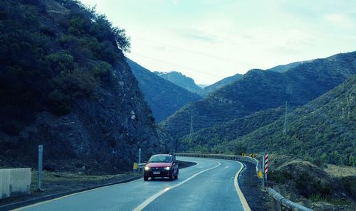 Cars on road by mountain against sky