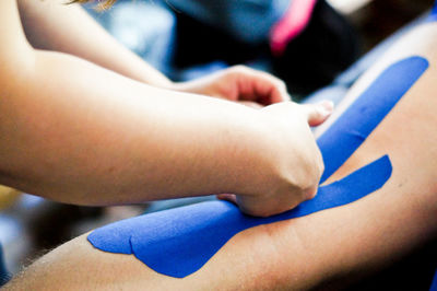 Cropped image of doctor applying bandage on leg of patient