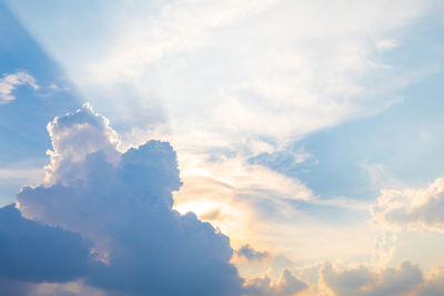 Low angle view of sunlight streaming through clouds