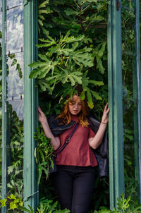 Portrait of young woman standing by plants