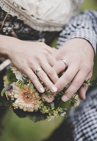 Midsection of couple with bouquet outdoors