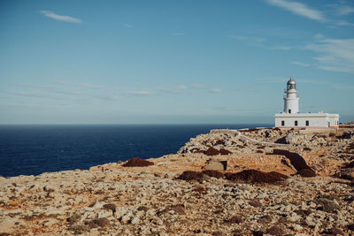 Lighthouse by sea against sky