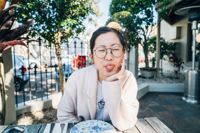 Woman sticking out tongue while sitting at table