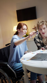 Young woman and man talking while looking at laptop