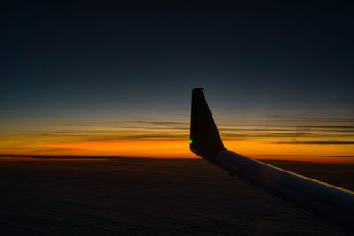 Airplane wing against sky during sunset