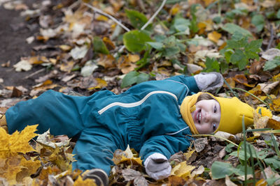 Full length of happy boy lying on leaves during autumn