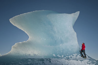 Woman climbinbg iceberg on the fjallsjoull glacier lagoon
